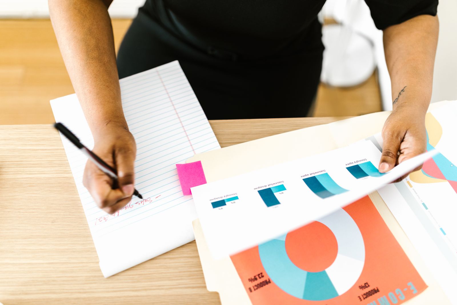 Person taking notes beside printed charts